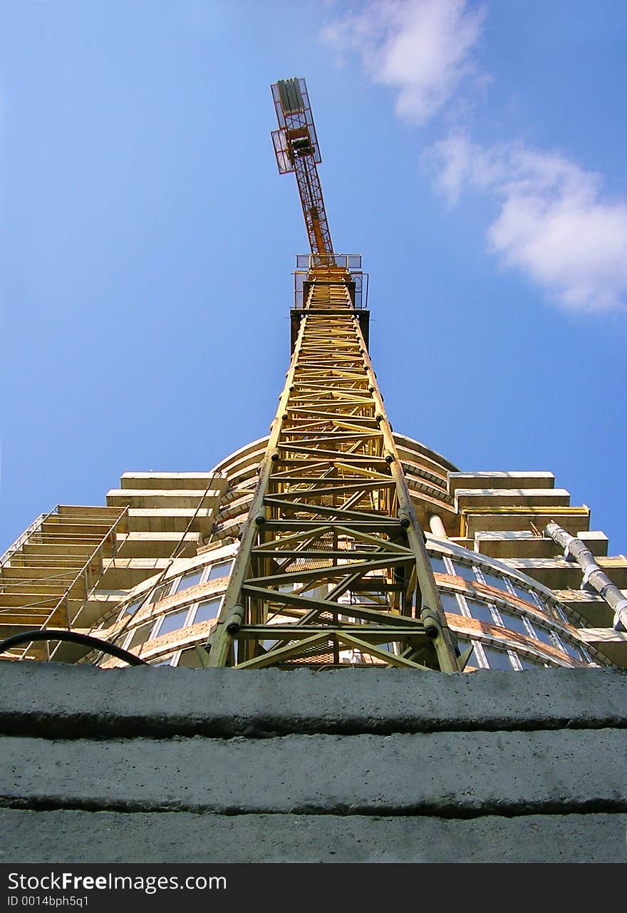 Tall orange crane constructing a new business building, center perspective view