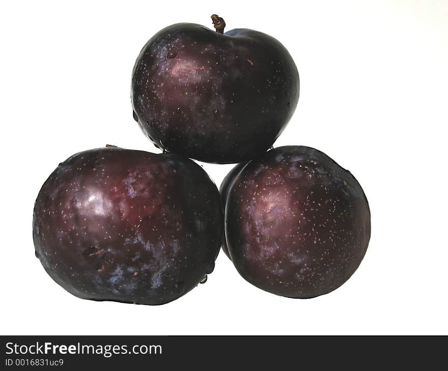 Three purple plums on white background