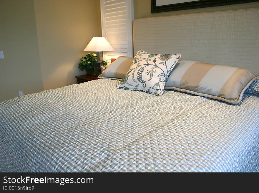 Beautiful blue bedroom, with silk pillows and quilted bedspread and headboard