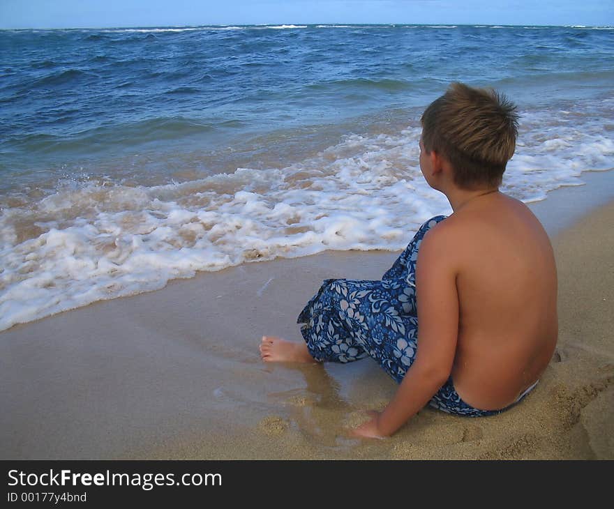 Preteen, adolescent boy waiting for the surf to roll in to the shoreline. Preteen, adolescent boy waiting for the surf to roll in to the shoreline.