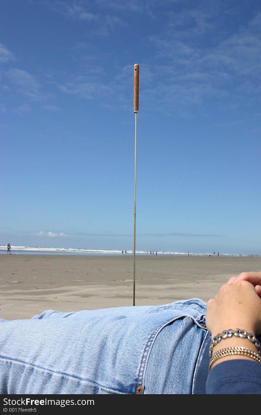 A large hotdog fork appears to be piercing the leg of my partner, sticking her to the beach. A large hotdog fork appears to be piercing the leg of my partner, sticking her to the beach