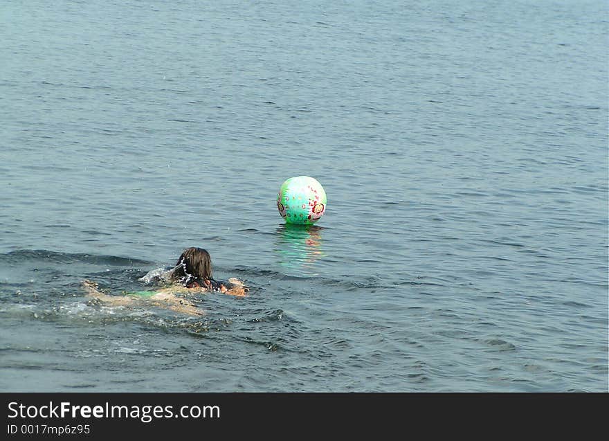 Girl rescueing her beach ball in the lake. Girl rescueing her beach ball in the lake.