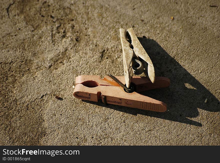 A pair of of old clothespegs on a concrete background.