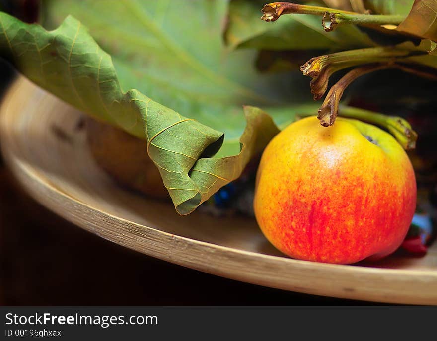 A plate with an apple and leaves. A plate with an apple and leaves