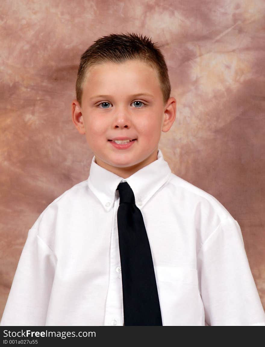 This is an image of a small 5 year ols boy posing in a coffee colored background. This is an image of a small 5 year ols boy posing in a coffee colored background.