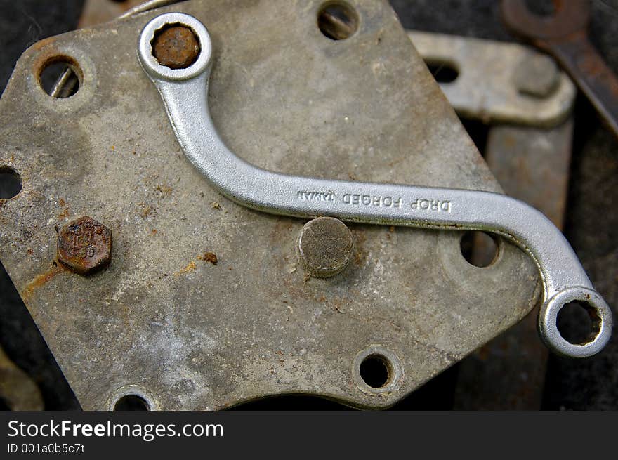 A new curved box end wrench on a old piece of equipment with a rusty bolt. A new curved box end wrench on a old piece of equipment with a rusty bolt