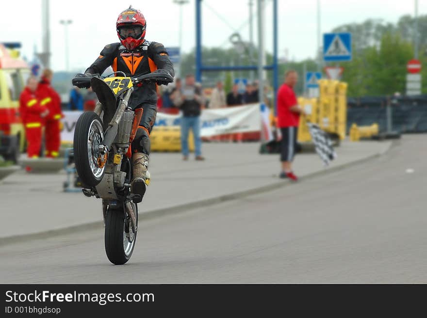 The joy of victory! Supermoto championships bike drives nose up over the finish line, checkered flag in the background. The joy of victory! Supermoto championships bike drives nose up over the finish line, checkered flag in the background.