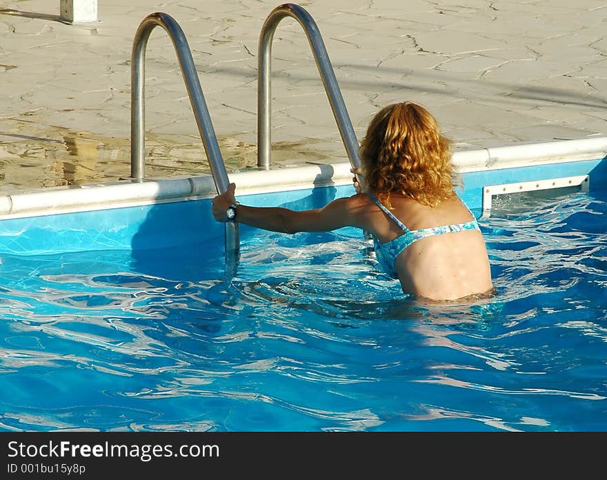 Woman getting into pool. Woman getting into pool