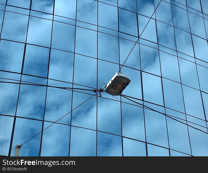 Street light with an office building in background. Glass facade is reflecting skies