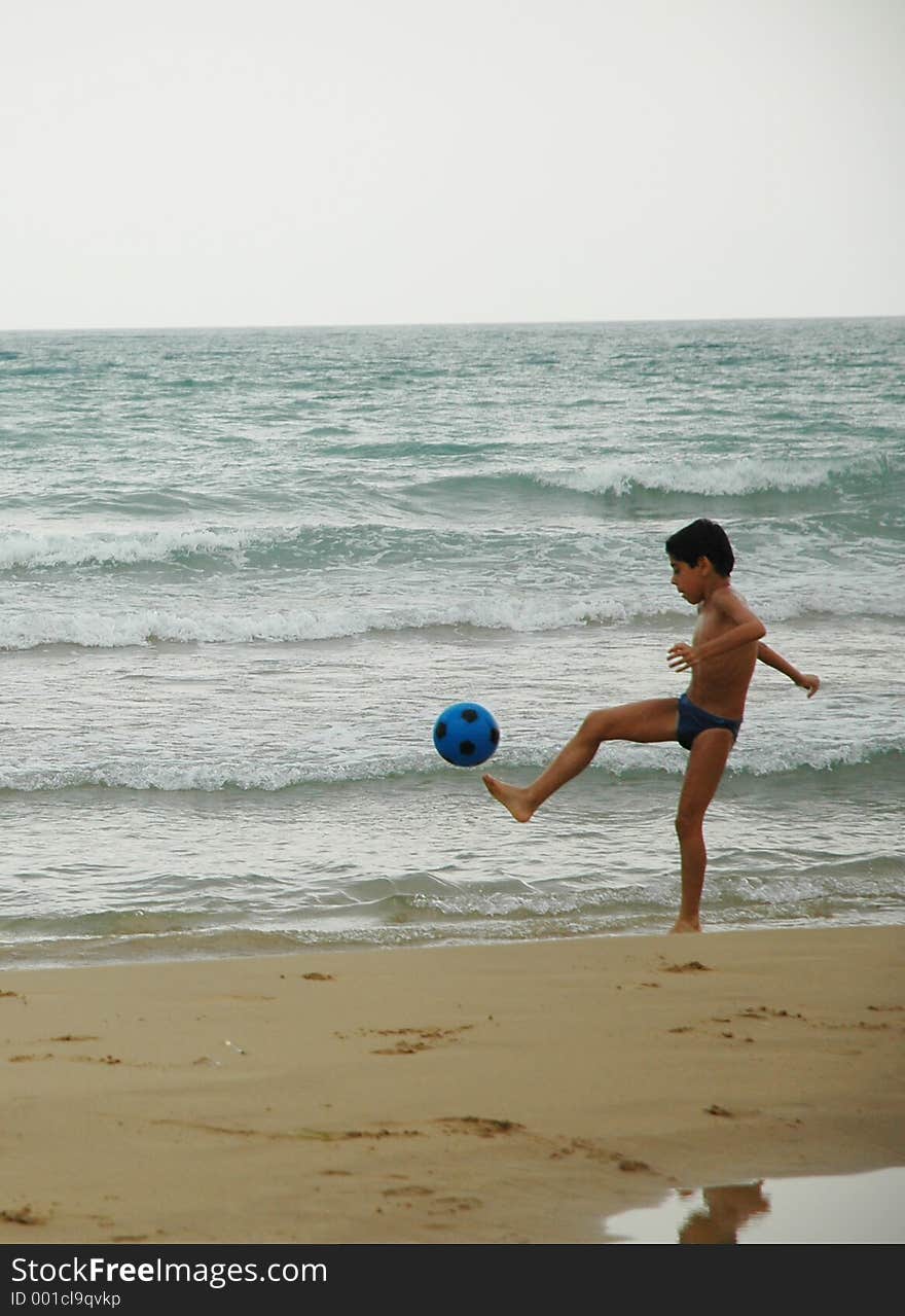 Young boy playing soccer on beach. Young boy playing soccer on beach