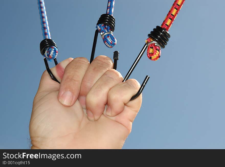 Hand pulling on 3 bungee cords tight. Hand pulling on 3 bungee cords tight