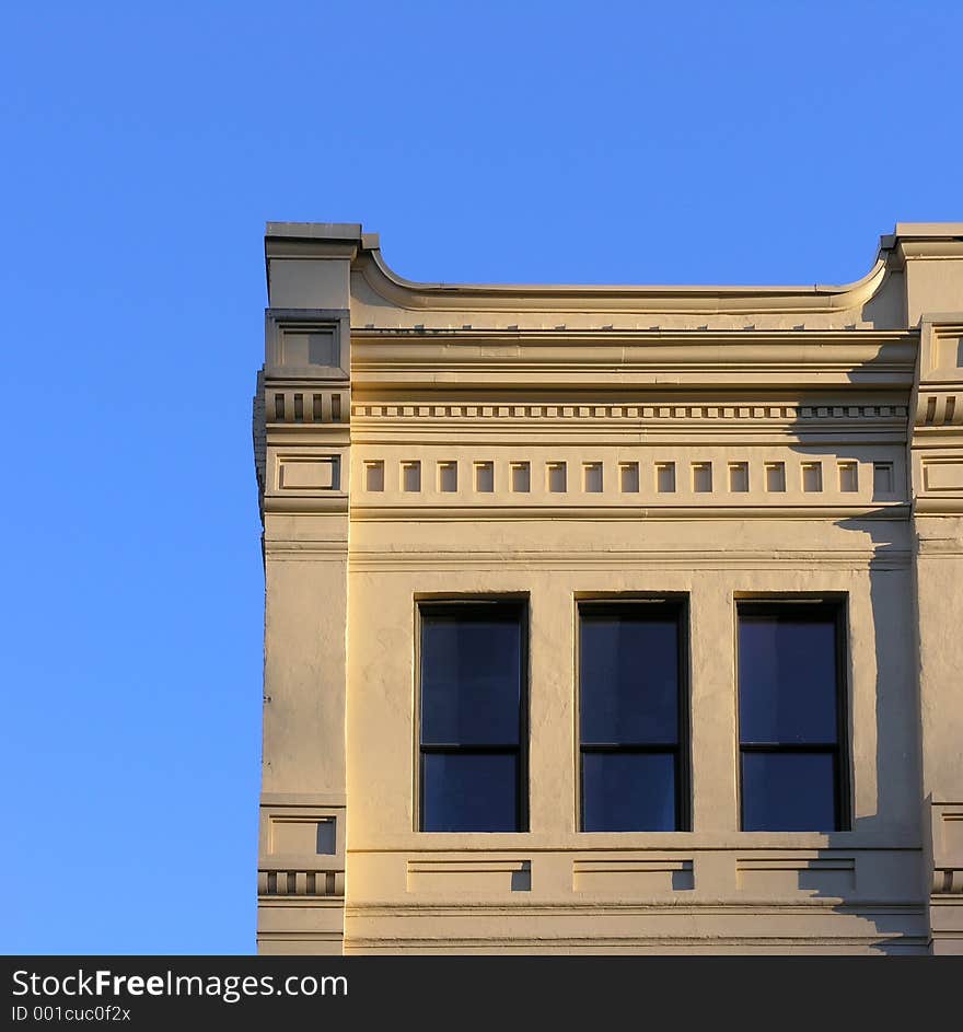 The corner of a building made golden by setting sunlight.