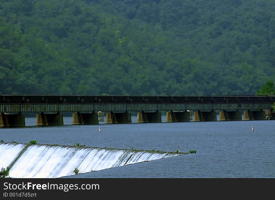 Man made water fall for a hydro-electric plant.. train on bridge in the background. Man made water fall for a hydro-electric plant.. train on bridge in the background.