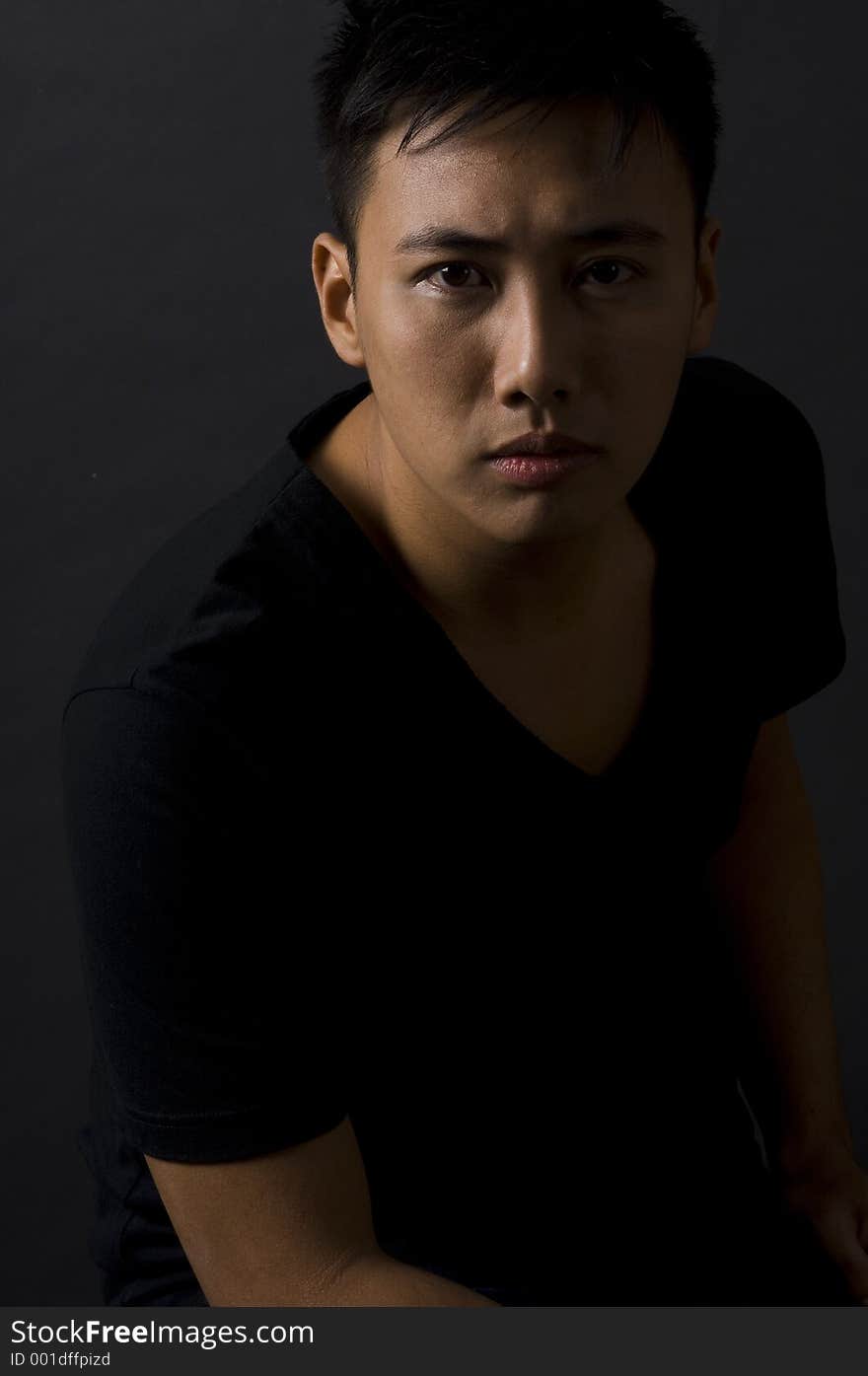 A moody and intense stare from a chinese male model in black. A moody and intense stare from a chinese male model in black