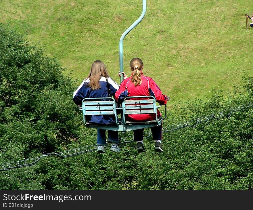 Two girls on a chair-lift in summer. Carpathian Mountains, Ukraine.