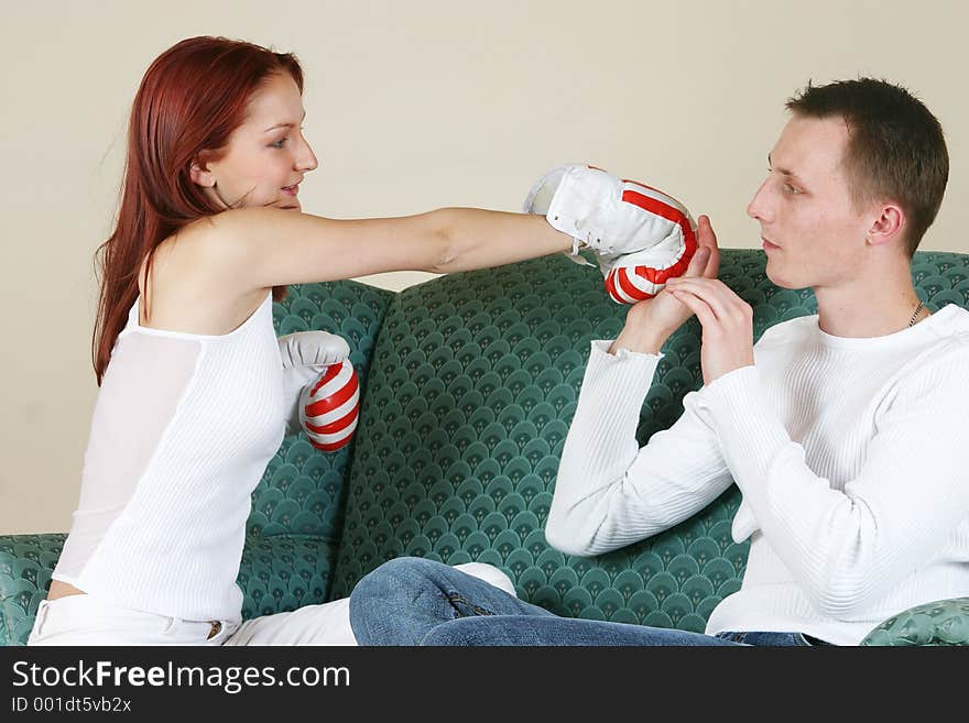 Couple fighting on a couch using boxing gloves. Couple fighting on a couch using boxing gloves