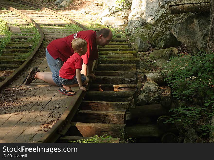 A father and son kneeling on an old railroad track. A father and son kneeling on an old railroad track.