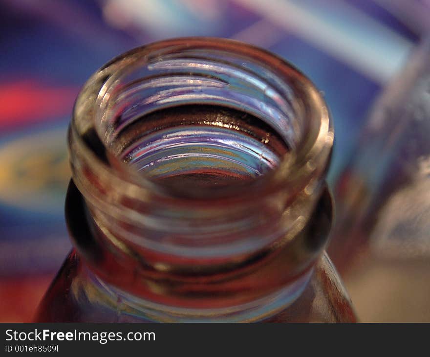 Colorful light plays on open bottle in an extreme close-up with very shallow depth of field focusing just inside the mouth of the bottle. Colorful light plays on open bottle in an extreme close-up with very shallow depth of field focusing just inside the mouth of the bottle.