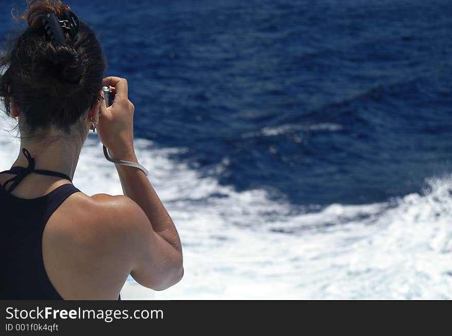 A girl takes a picture from a boat. A girl takes a picture from a boat