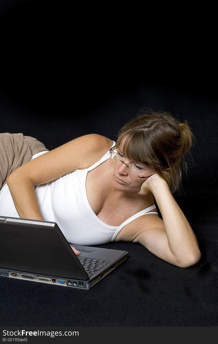 Pregnant woman lying down surfing the web on a laptop. Pregnant woman lying down surfing the web on a laptop