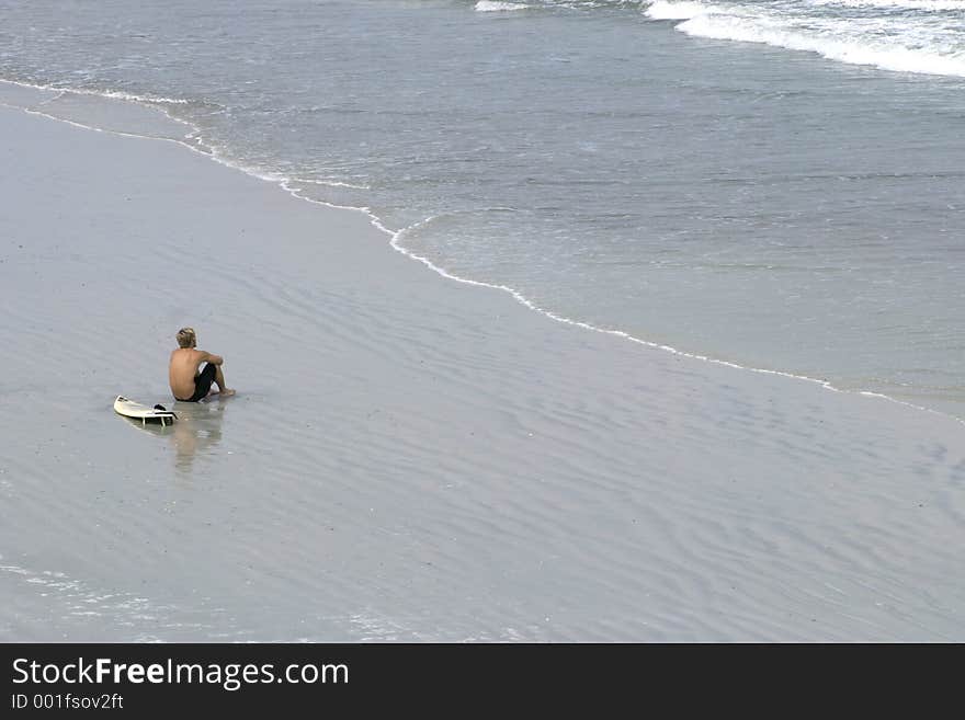 Young male surfer looking out at the ocean. Young male surfer looking out at the ocean.