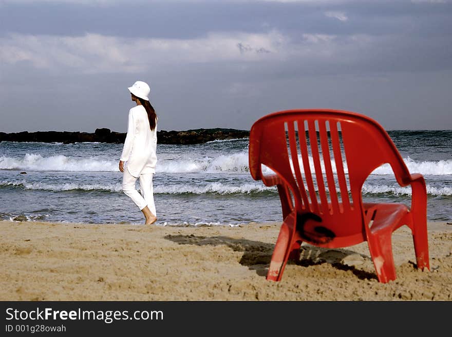 Lady in white on the seashore with red chair