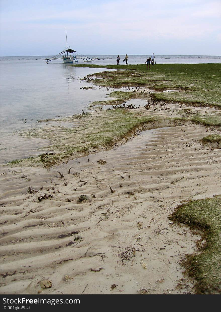 Crossing beach at low tide to board banca in the visayas philippines. Crossing beach at low tide to board banca in the visayas philippines