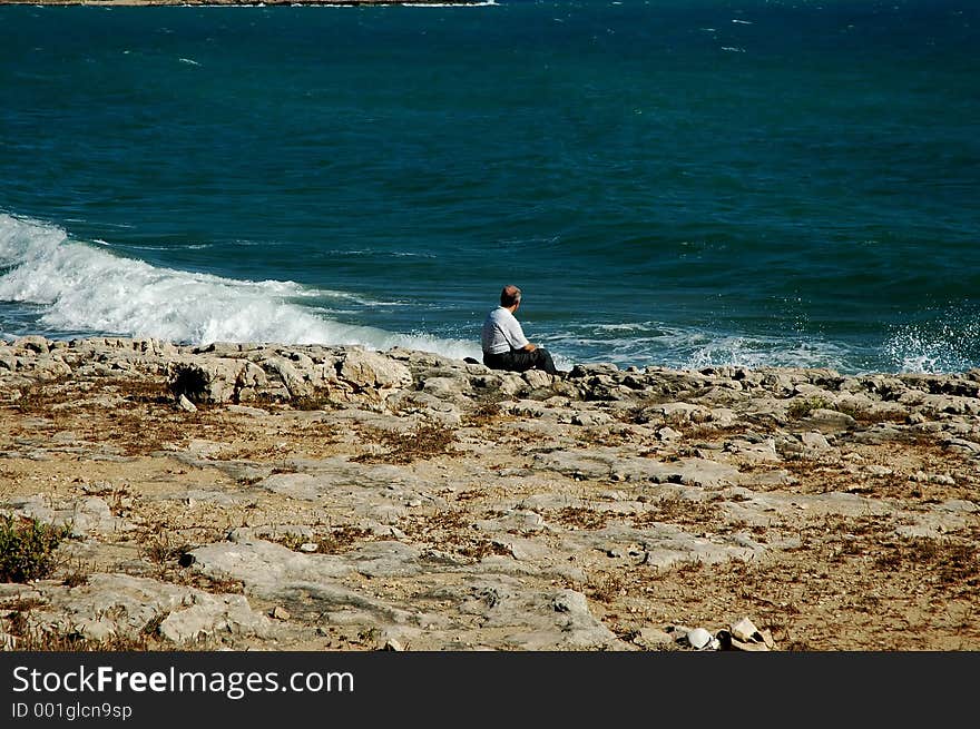 Man sitting on the rocks looking out the sea. Man sitting on the rocks looking out the sea