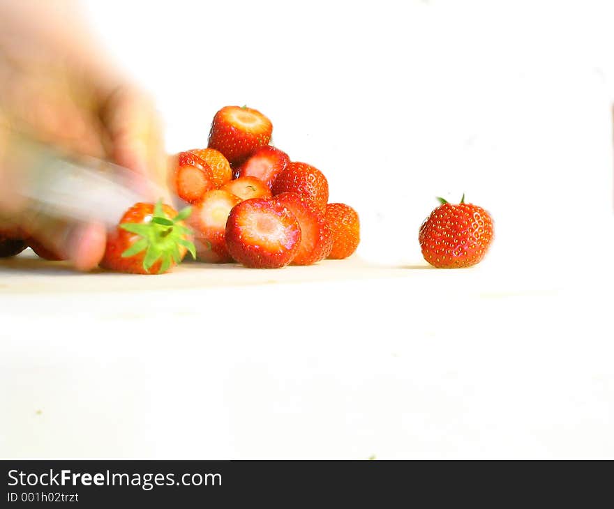 Blurred hand slicing fresh strawberries - isolated. Blurred hand slicing fresh strawberries - isolated