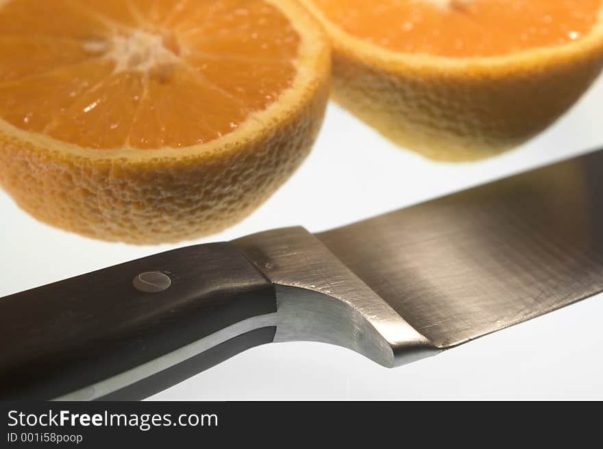 Closeup of sliced orange and knife on white background
