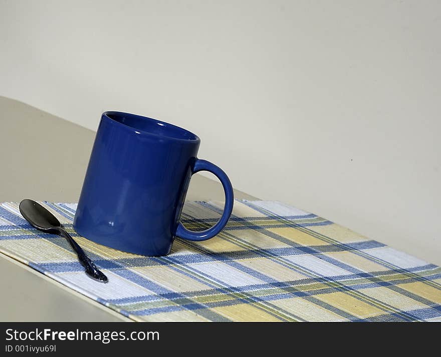 A close-up view of a coffee mug and spoon sitting on a placemat. A close-up view of a coffee mug and spoon sitting on a placemat