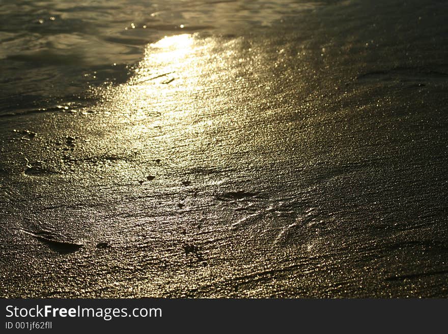 A shot of the reflection of evening light on wet sand of the beach