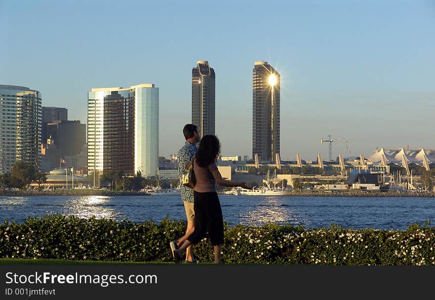 Couple taking a romantic sunset walk on Coronado Island with San Diego skyline background. Couple taking a romantic sunset walk on Coronado Island with San Diego skyline background.