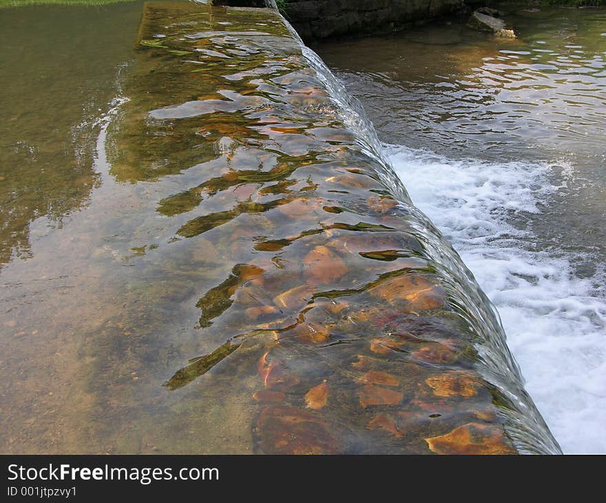 Small waterfall over stone ledge. Small waterfall over stone ledge