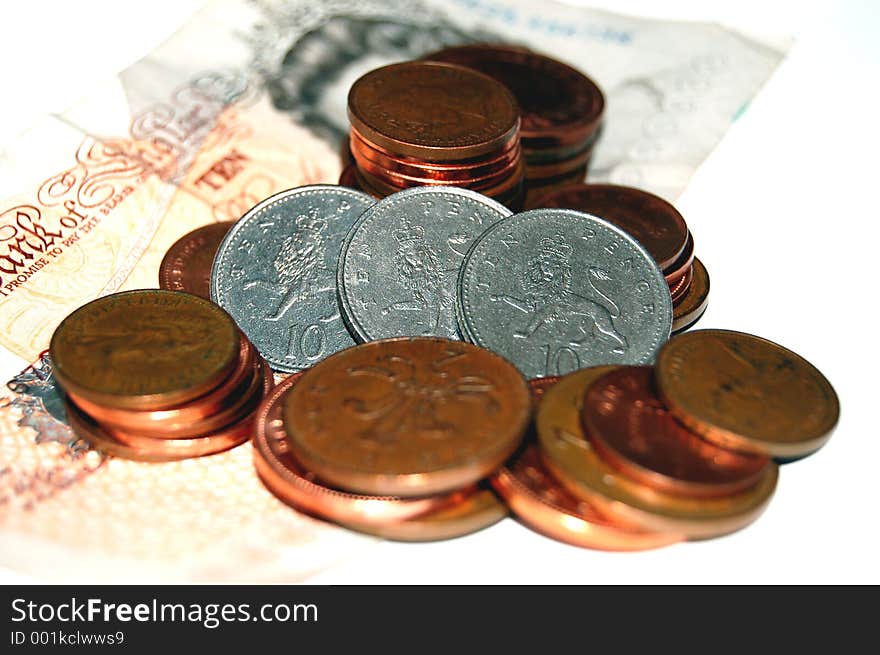 Three ten pence coins lined in the midst of ten pound note and other pennies. Three ten pence coins lined in the midst of ten pound note and other pennies.