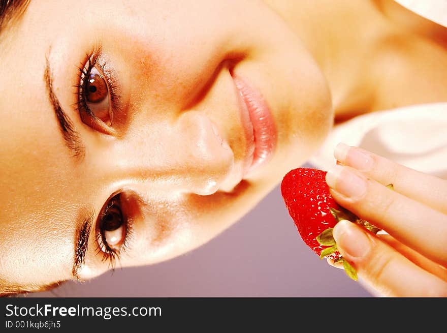 Attractive girl enjoying a refreshing, tasty strawberry. Attractive girl enjoying a refreshing, tasty strawberry