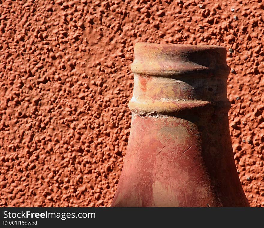 A clay chimney against a red stucco wall. A clay chimney against a red stucco wall.