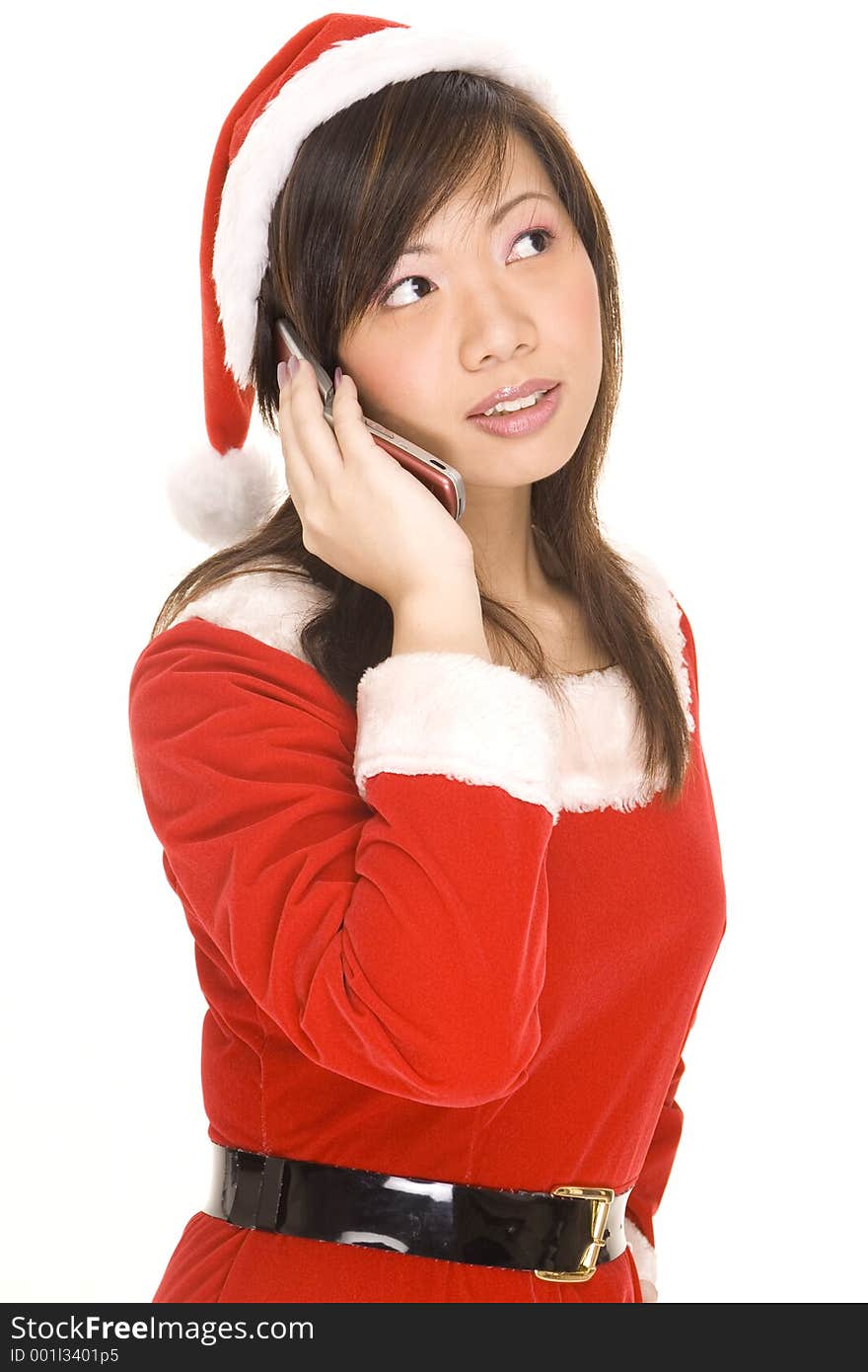 A cute asian woman dressed in a santa costime listens on the phone. A cute asian woman dressed in a santa costime listens on the phone