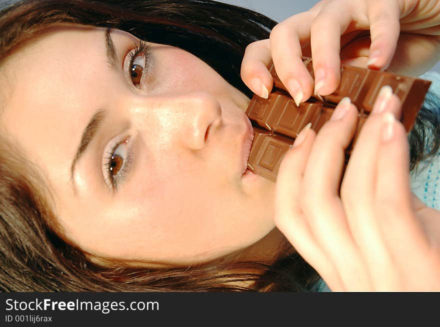 Beautiful girl biting with satisfaction from a chocolate bar. Beautiful girl biting with satisfaction from a chocolate bar