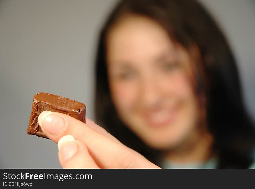 Close-up of a piece of chocolate held by a girl smiling in the background. Close-up of a piece of chocolate held by a girl smiling in the background