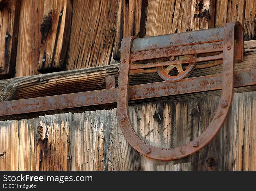 Rusted old door pulley on weathered barn door