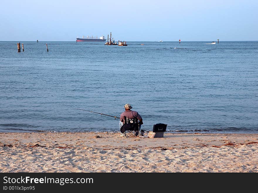 A man and his fishing pole relaxing on the beach. A man and his fishing pole relaxing on the beach.