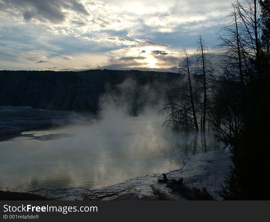 Trees and shore in mist around Mammoth Hot Springs at sunrise - Yellowstone National Park, Wyoming. Trees and shore in mist around Mammoth Hot Springs at sunrise - Yellowstone National Park, Wyoming