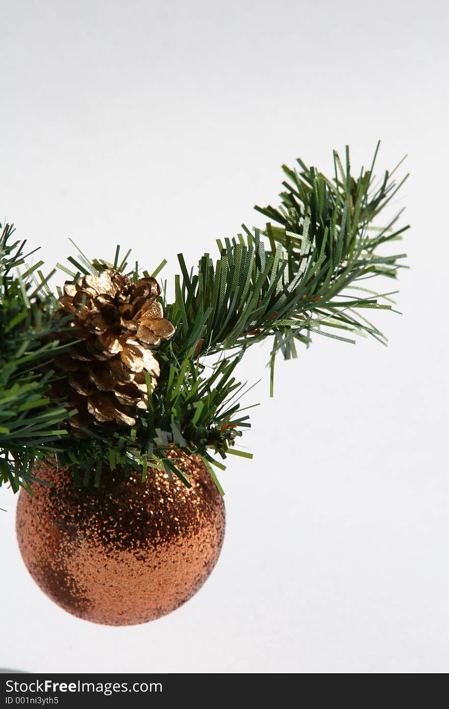 Bronze bauble hanging on greenery sprig with gold fir cone