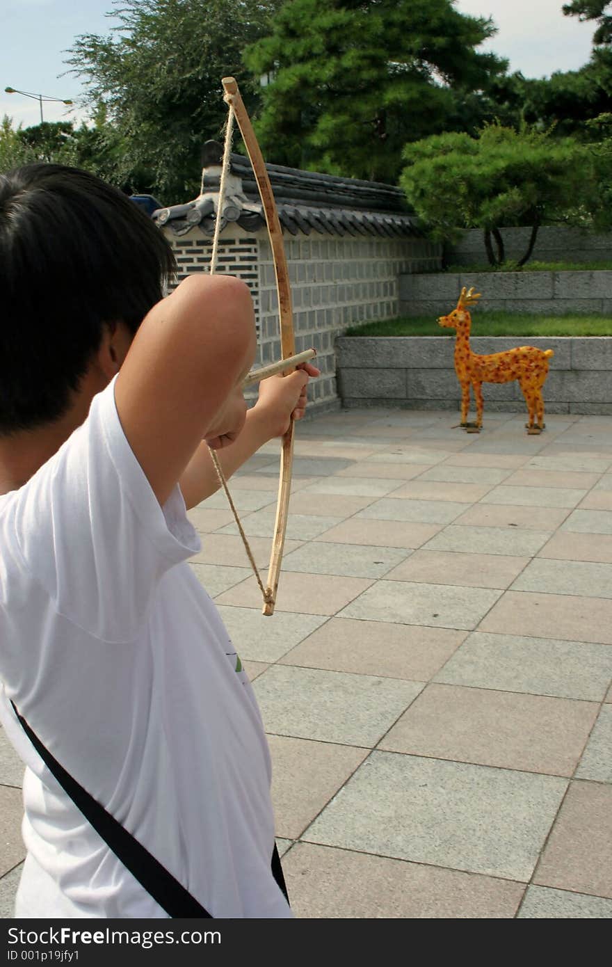 Boy with bow and arrow aiming at model giraffe. Boy with bow and arrow aiming at model giraffe