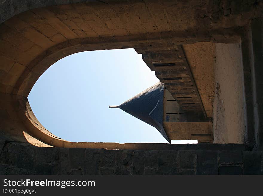 View at Carcassonne castle tower through an old stone archway in a sunny summer day with a clear blue sky. View at Carcassonne castle tower through an old stone archway in a sunny summer day with a clear blue sky