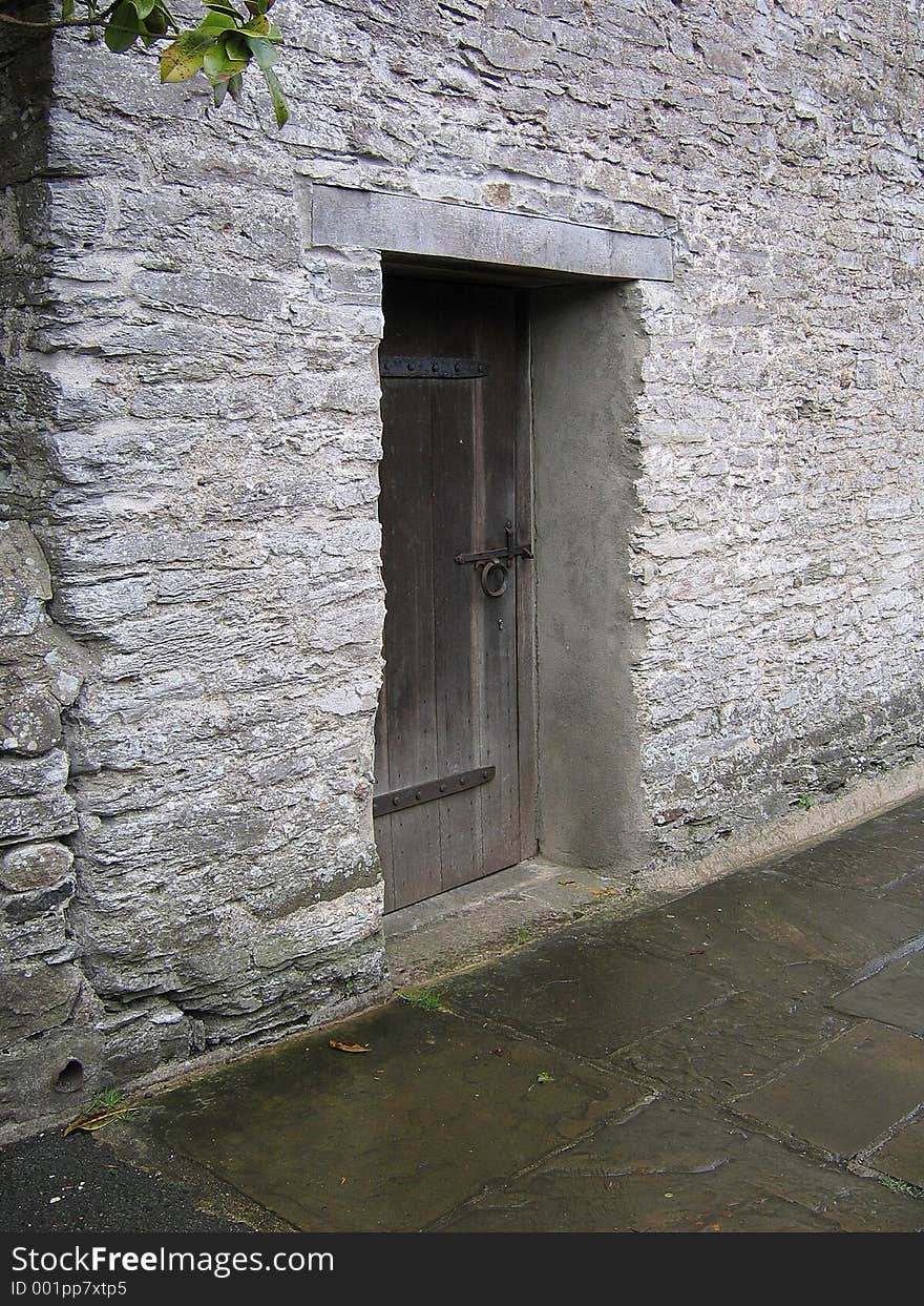 Old wooden door, set against a thick stone wall on a path near Buckfast Abbey in Devon, England. Old wooden door, set against a thick stone wall on a path near Buckfast Abbey in Devon, England