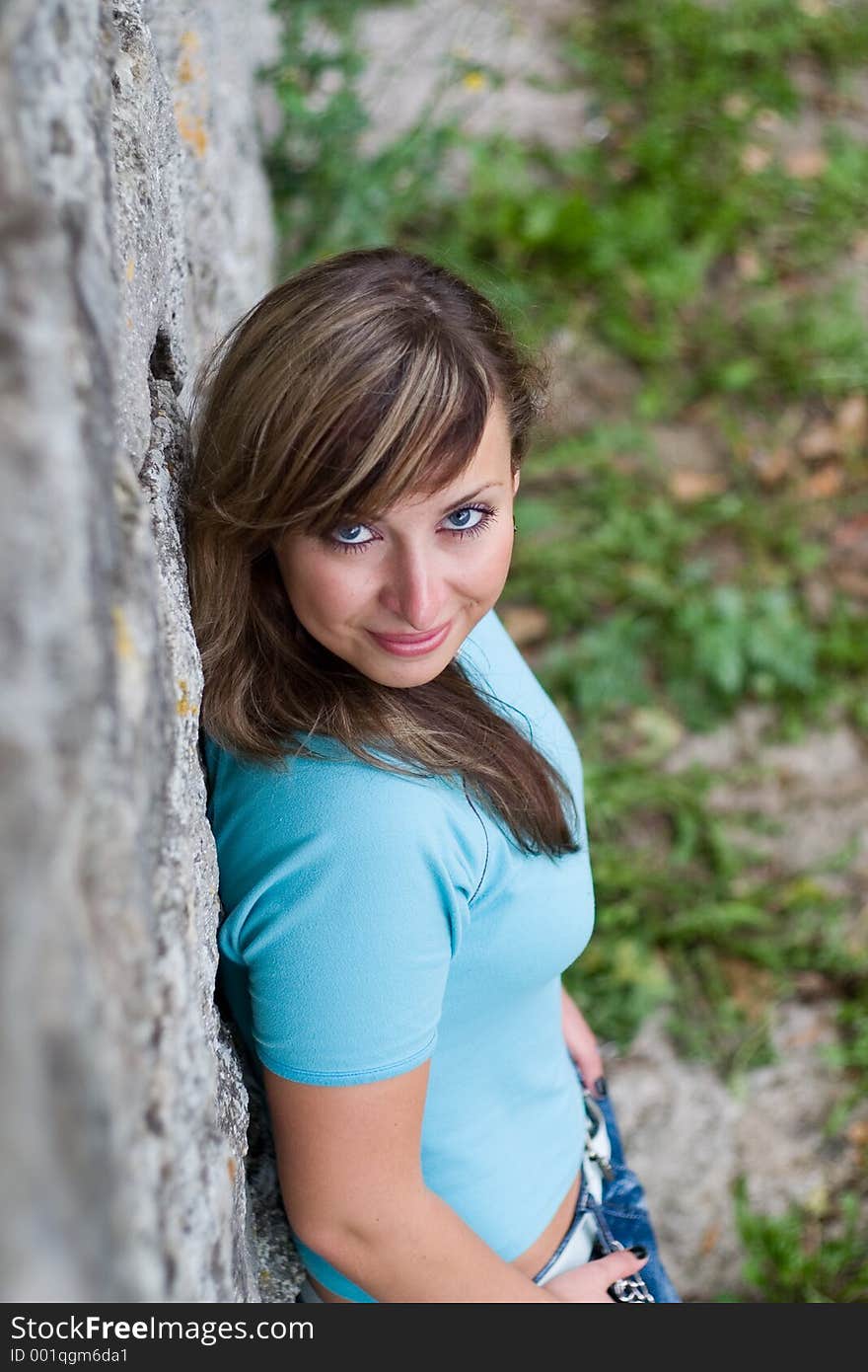 Young beautiful girl standing near brick wall and smiling. Young beautiful girl standing near brick wall and smiling