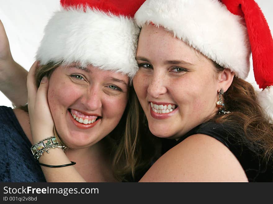 Two pretty girls in Santa hats laughing. Two pretty girls in Santa hats laughing.