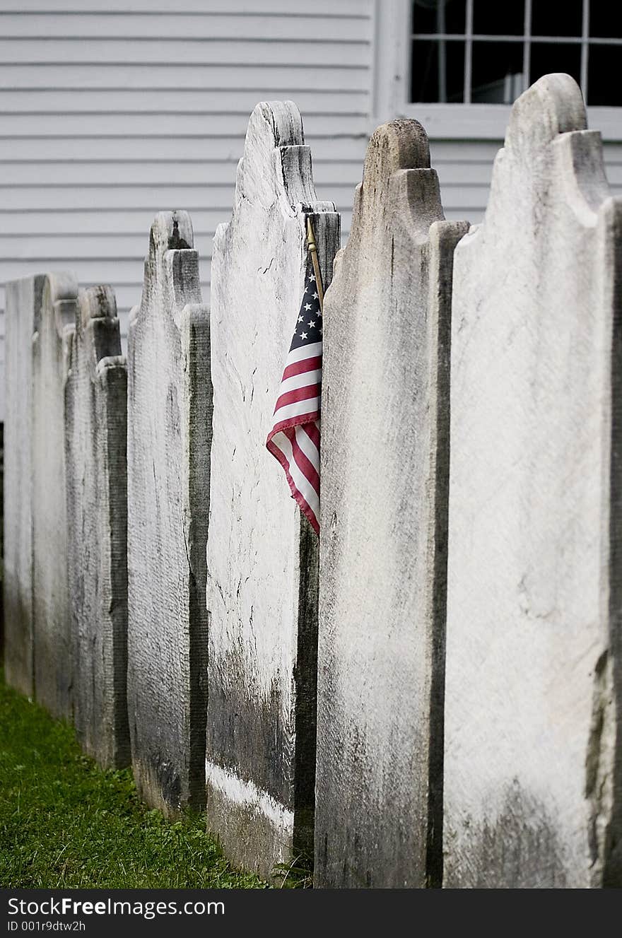 A lonely American flag is placed in the midst of unmarked tombstones. A lonely American flag is placed in the midst of unmarked tombstones